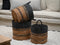 Three woven baskets with handles on a textured surface with a sofa in the background