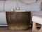 A round, ribbed dark brown wooden coffee table styled in a modern living room setting with a light beige sectional sofa in the background.