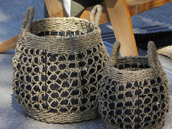 Two woven baskets with a geometric pattern on a textured surface.