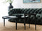 lounge room with a green sofa, two black coffee tables and a large jute rug