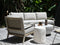 Outdoor furniture set with a sofa, chairs, and tables on a wooden deck.