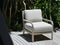 Chair with light gray cushions on a wooden deck surrounded by greenery