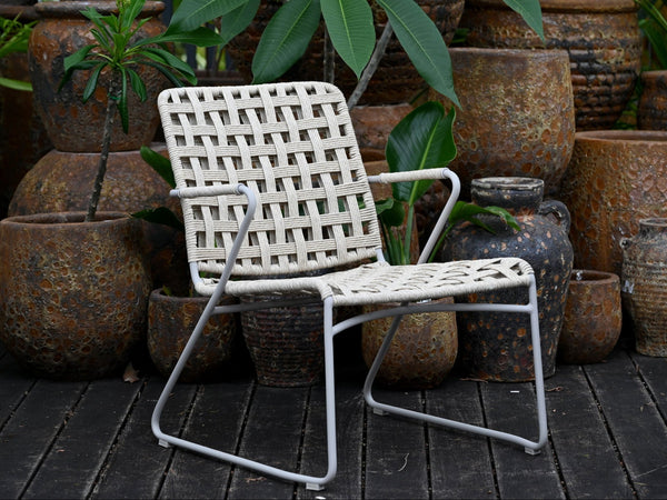 White wicker chair on a wooden deck with rustic pots and plants in the background
