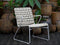 White wicker chair on a wooden deck with rustic pots and plants in the background