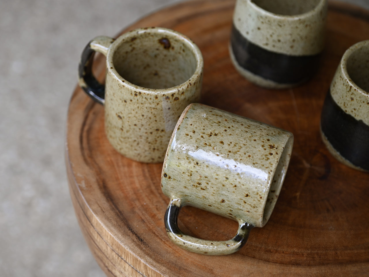 Set of ceramic mugs with speckled glaze on a wooden surface