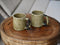 Two ceramic mugs on a wooden surface with a neutral background