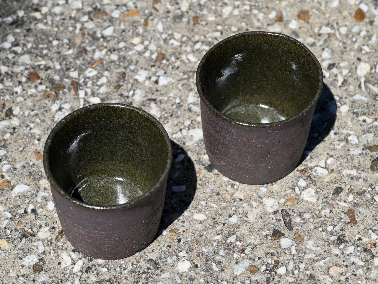 Two dark ceramic cups on a textured surface