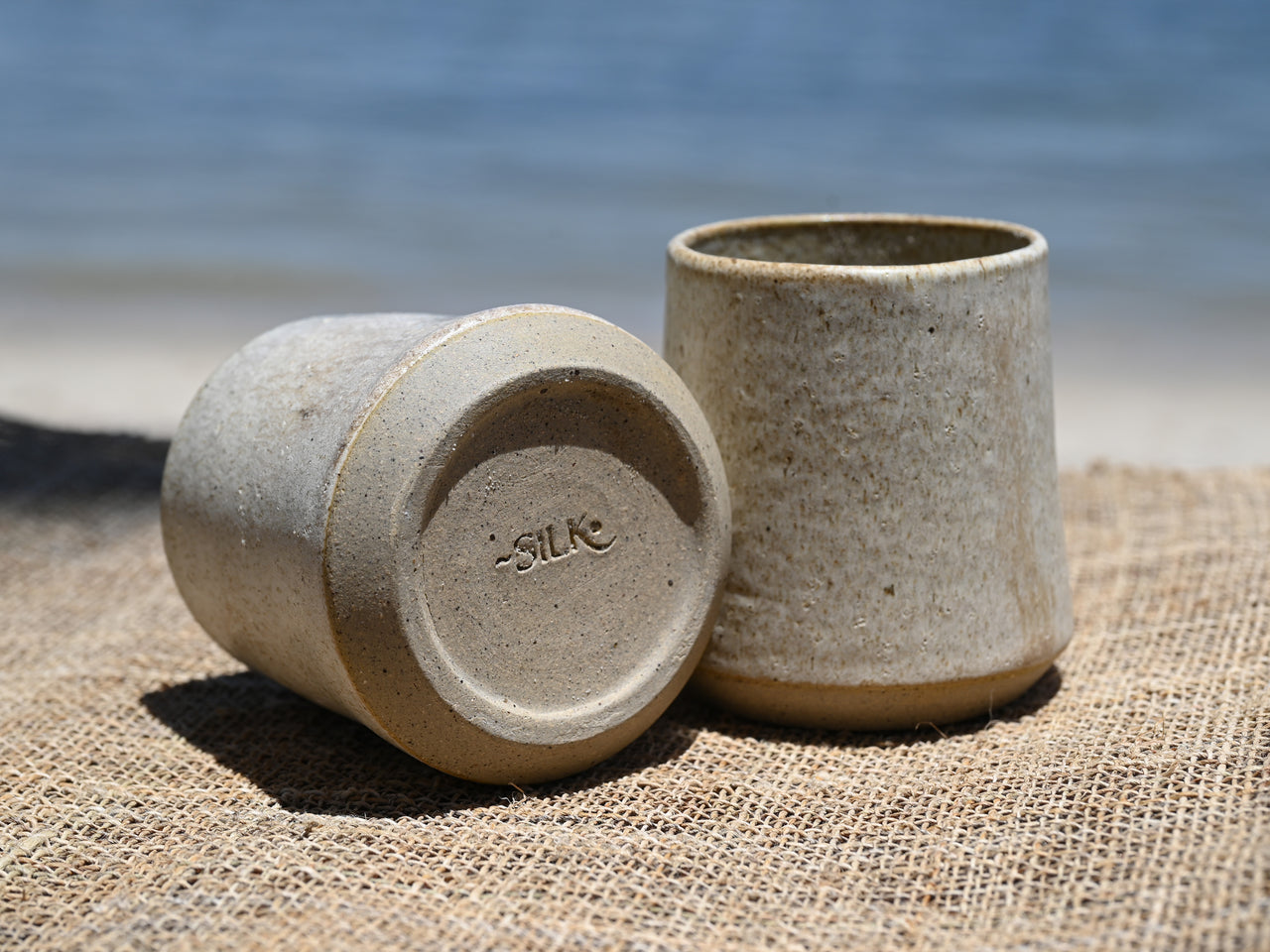 Two ceramic cups on a textured surface with a blurred natural background