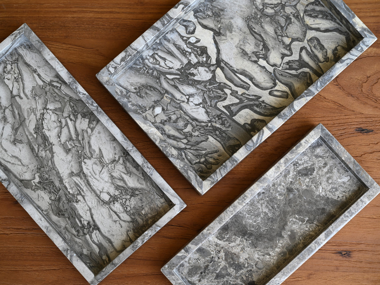 Three rectangular marble trays on a wooden surface