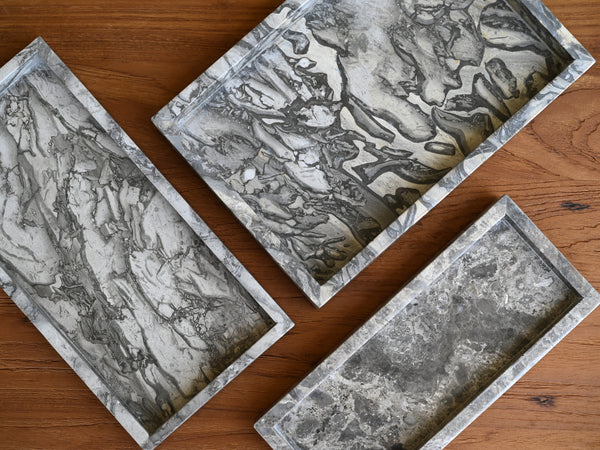 Three rectangular marble trays on a wooden surface