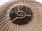 Close-up of a woven basket with a metallic emblem in the center.